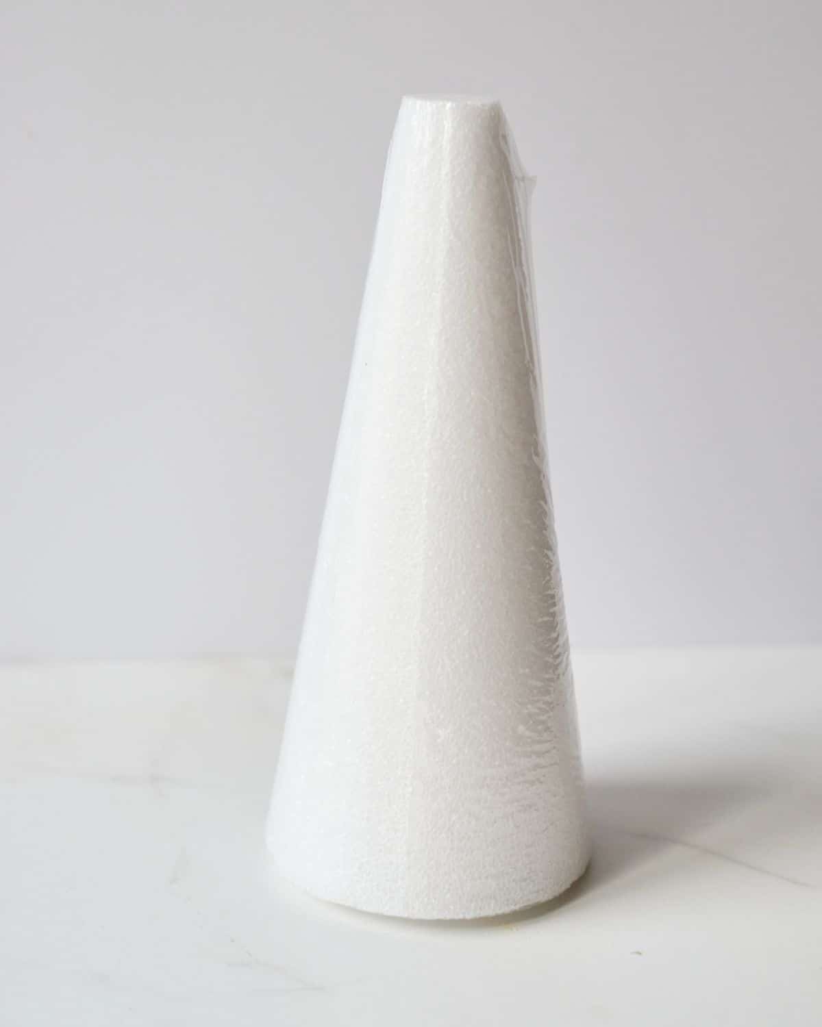 White Styrofoam cone used to make Christmas tree on a white marble background